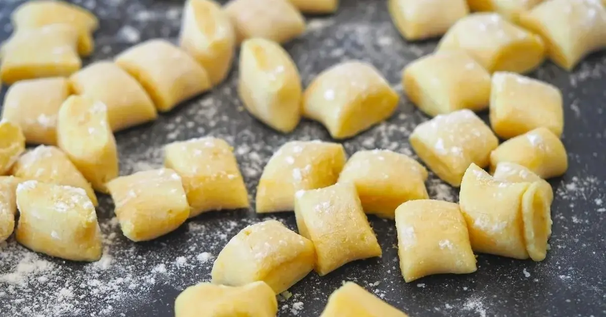 Ciasto na kopytka posypane mąką na blacie.