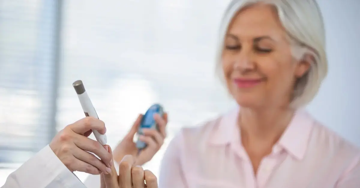 Kontrola poziomu cukru u siwowłosowej kobiety w jasnoróżowej koszuli
