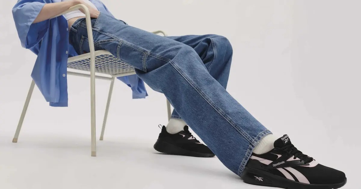 Mężczyzna w czarnych adidasach rozparty na krześle
