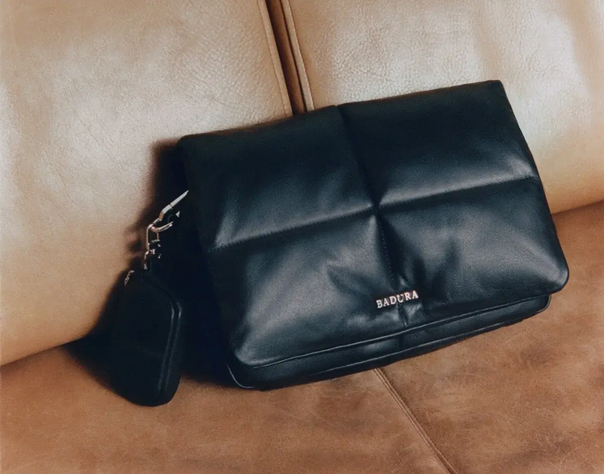 Na jasnej skórzanej kanapie czarna torebka damska elegancka