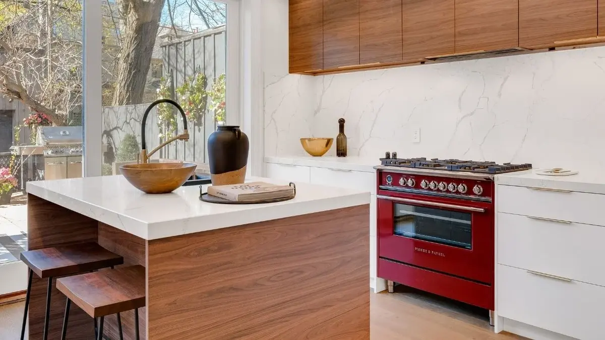 Czerwona kuchenka gazowa wśród białych i drewnianych szafek w kuchni