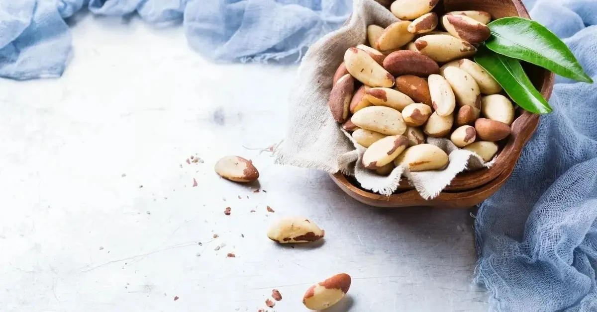 orzechy brazylijskie w brązowej misce obok błękitnego materiału ozdobnego