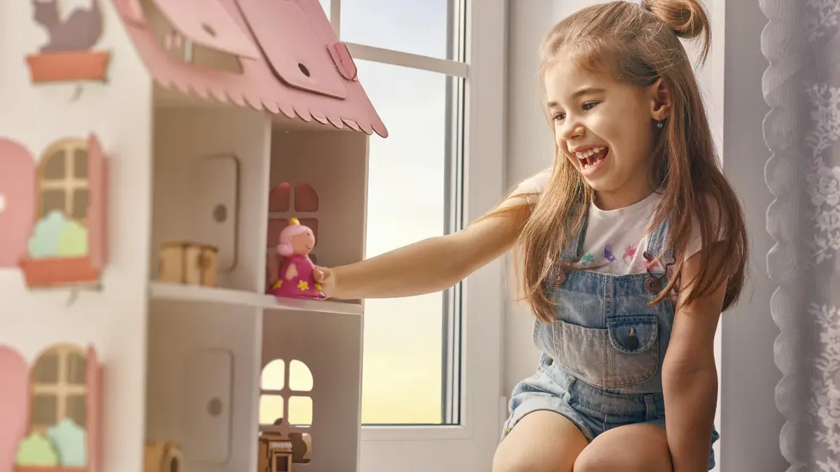 Dziewczynka bawi się domkiem, który dostała na Dzień Dziecka.