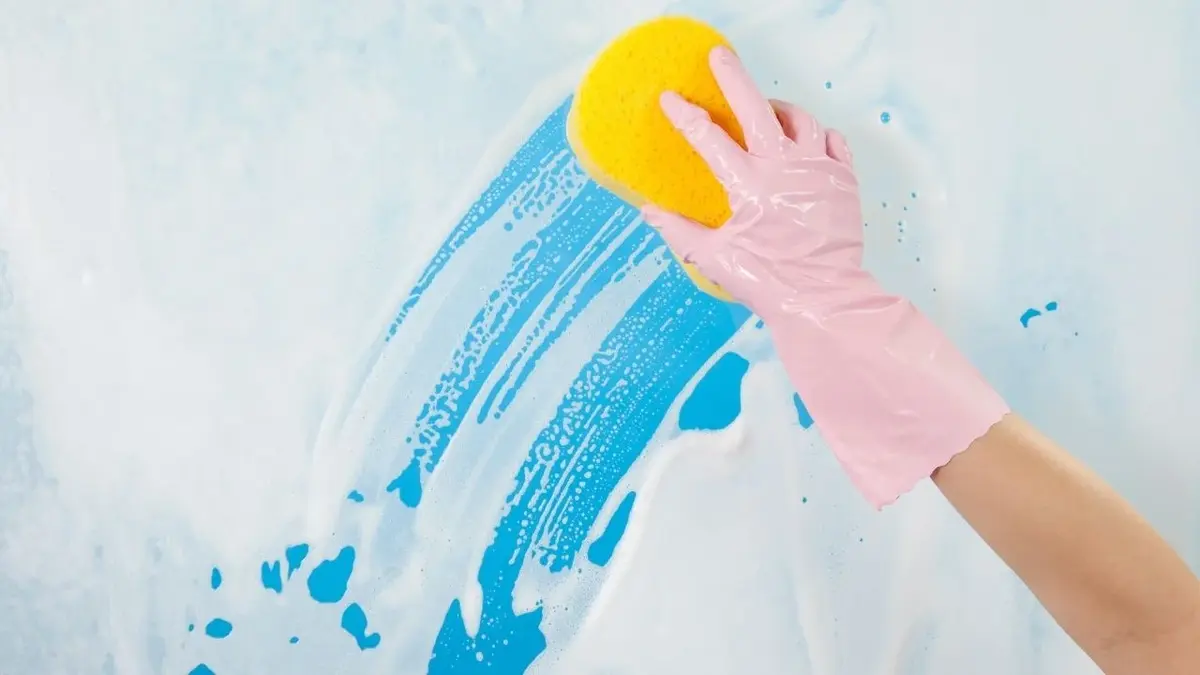 kobieta w różowej rękawiczce myjąca okna płynem DIY przy użyciu żółtej gąbki