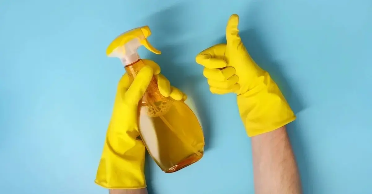 domowy płyn do mycia okien w żółtej butelce z atomizerem trzymany w rękach 
