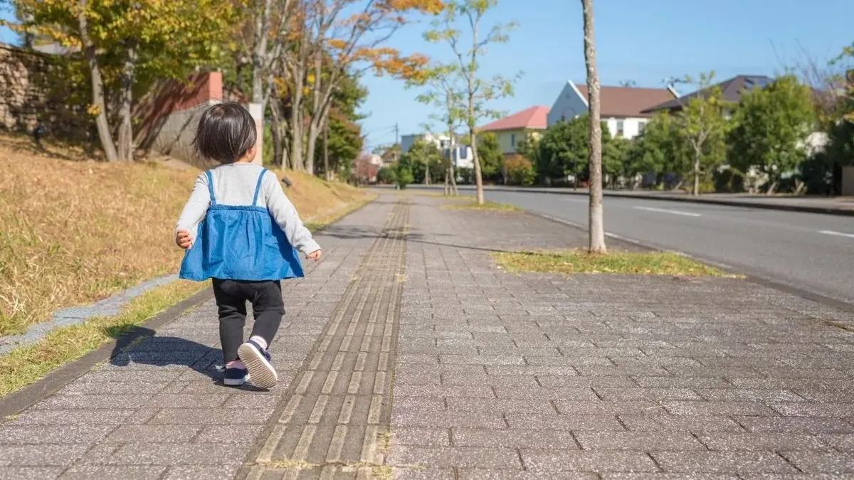 Dwuletnie dziecko idzie samo po chodniku.
