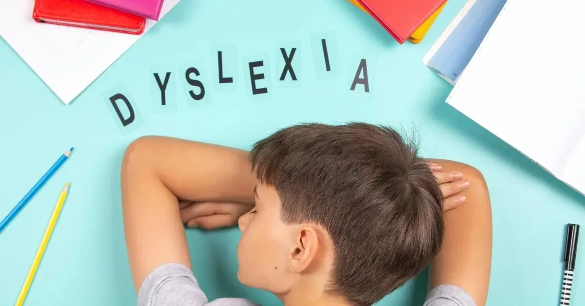 dysleksja chłopiec leżący na błękitnym blacie zeszyty i literki obok