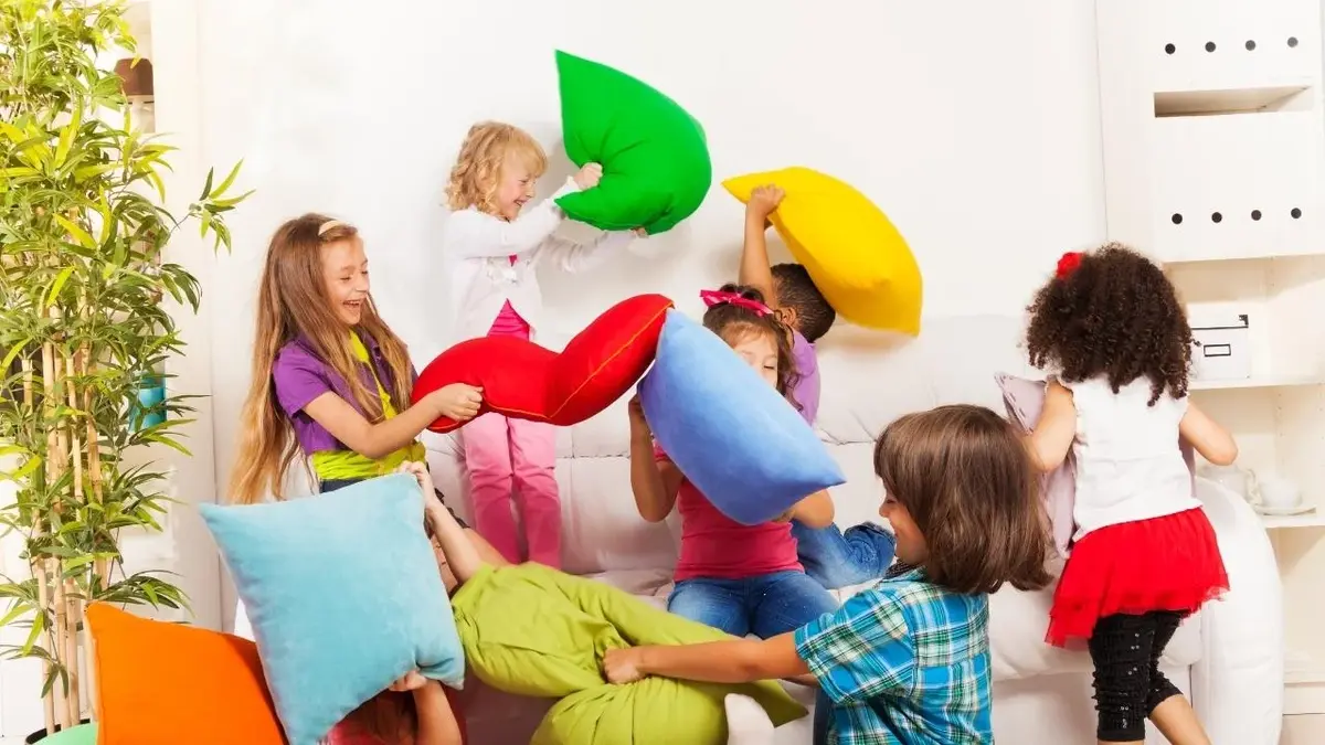 Dzieci bawią się kolorowymi poduszkami w domu.