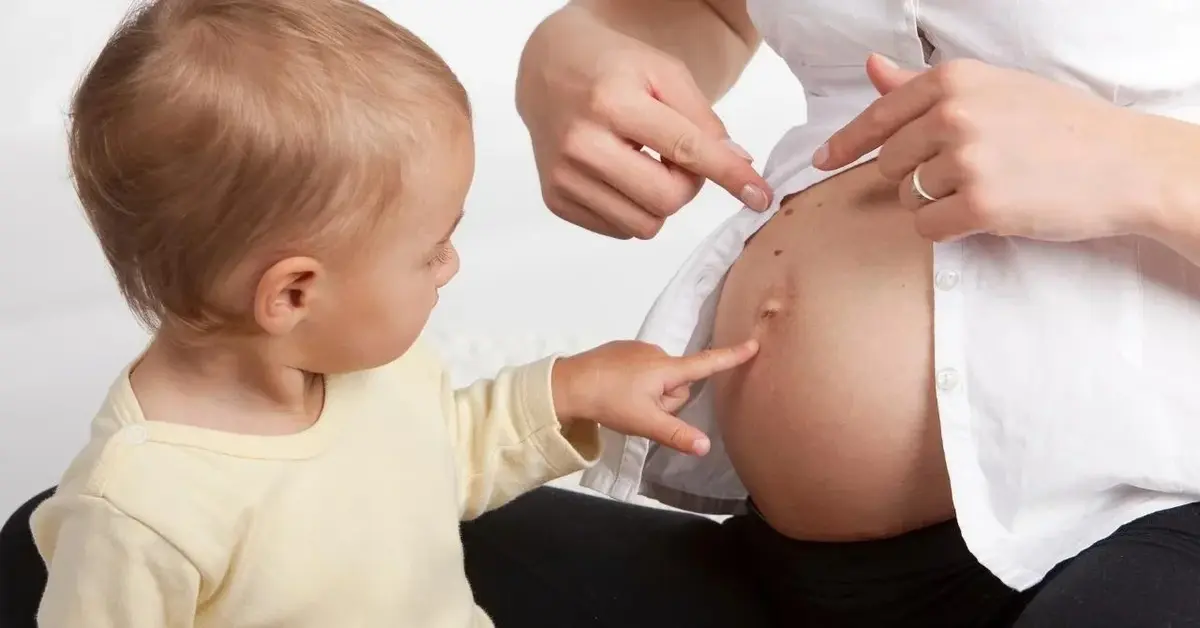 Dziecko czeka na rodzeństwo - pokazuje na ciążowy brzuch mamy.