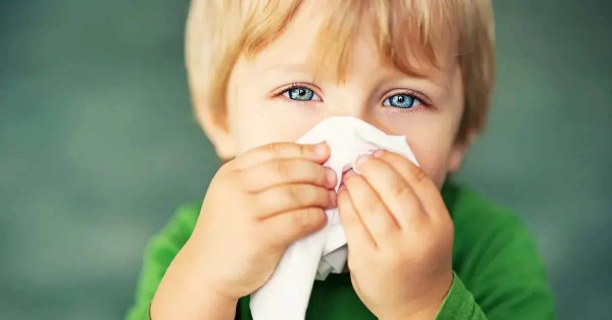 Dziecko z katarem wyciera nos w chusteczkę.
