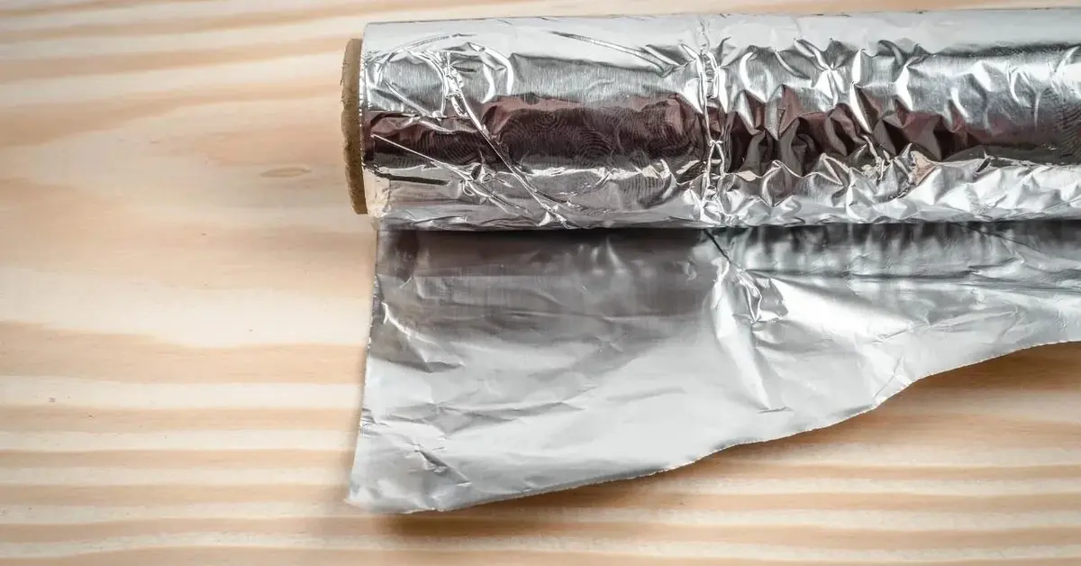 Folia aluminiowa, której jedna strona trzyma ciepło, a druga zimno, leży na stole.