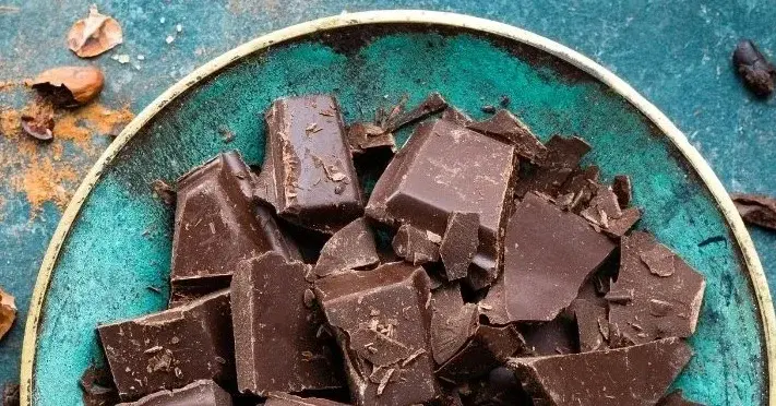 gorzka czekolada na niebieskim talerzy w otoczeniu ziaren kakao