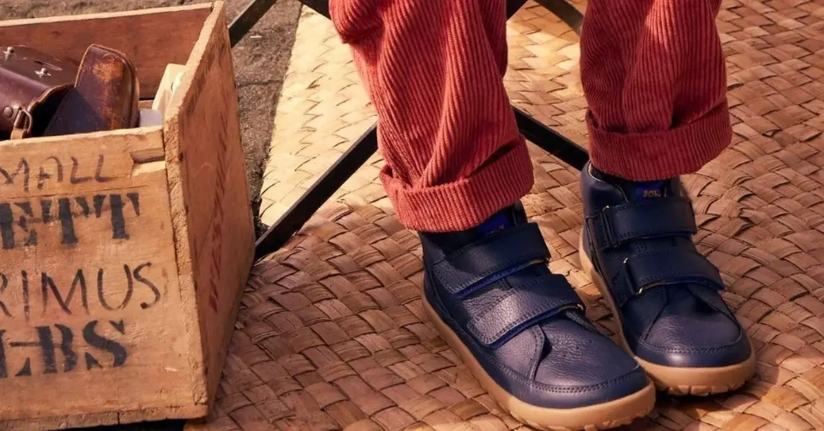 Dziecko w granatowych butach barefoot przy drewnianej skrzynce