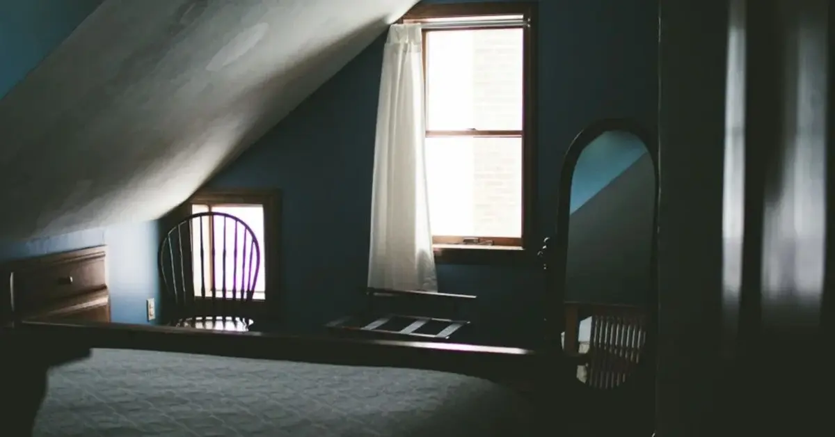 Ciemna sypialnia z wąskim oknem i dużym lustrem