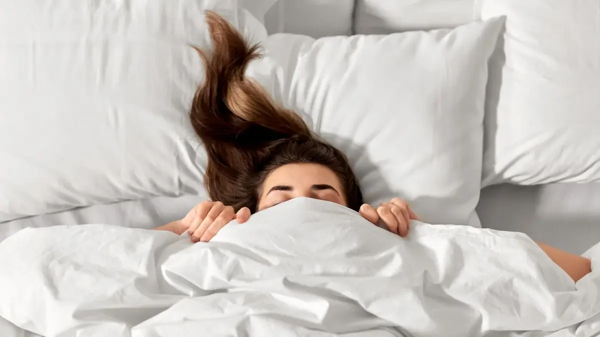 Kobieta w łóżku z przykryta kołdra twarzą 