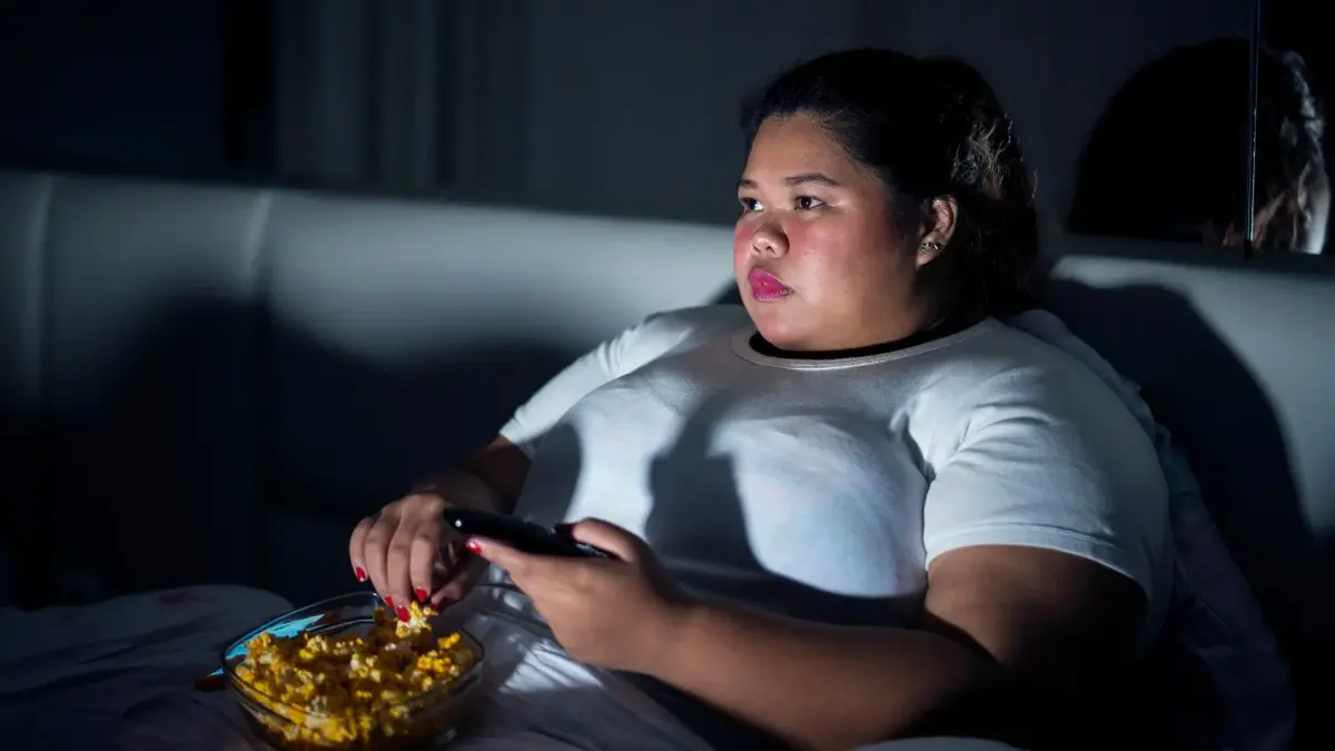 Otyła kobieta oglądająca w nocy telewizję i jeżdżąca pizzę