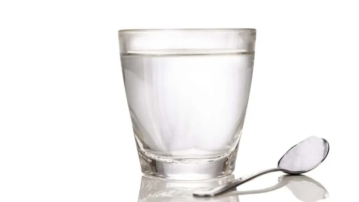 Szklanka wody, obok łyżeczka z solą 