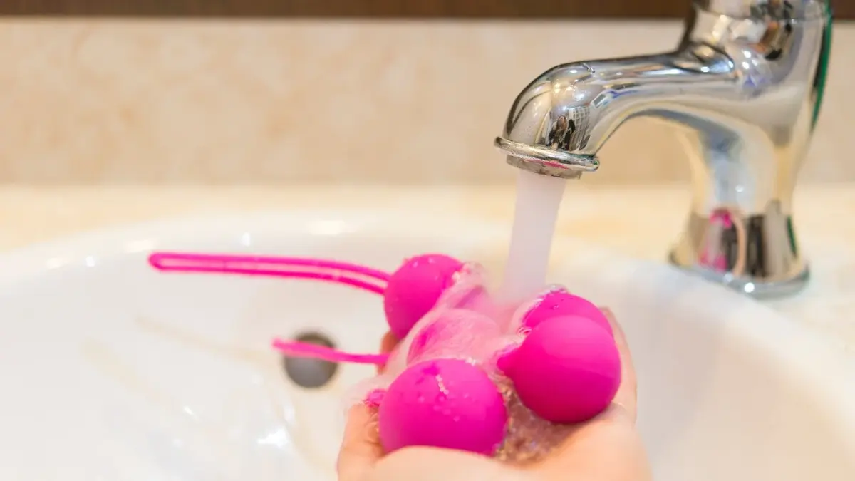 Różowe kulki gejszy trzymane w dłoniach i myte w umywalce