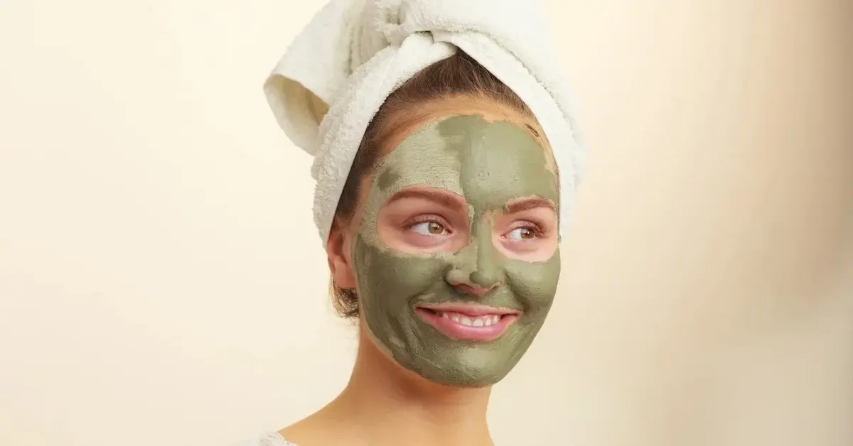 Kobieta z maseczką z zielonej glinki na twarzy 