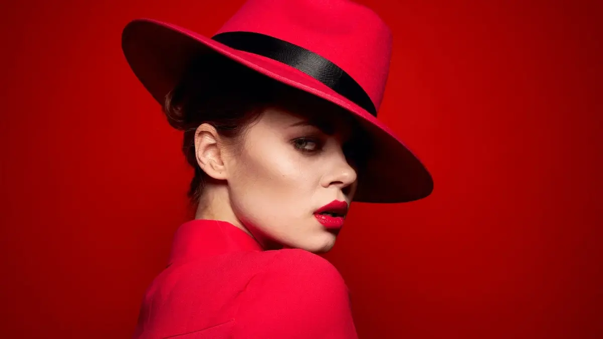 Kobieta w czerwonej sukience i czerwonym kapeluszu na czerwonym tle 