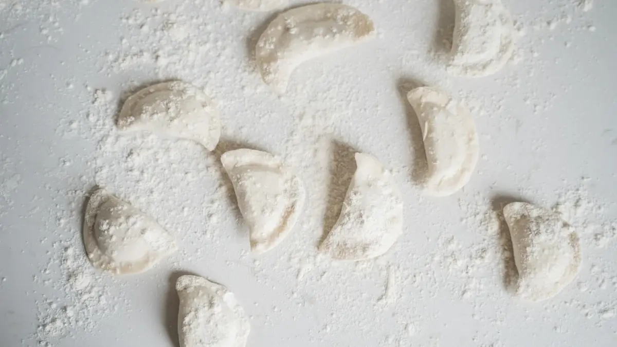 Pierogi na białym blacie obsypane mąką 