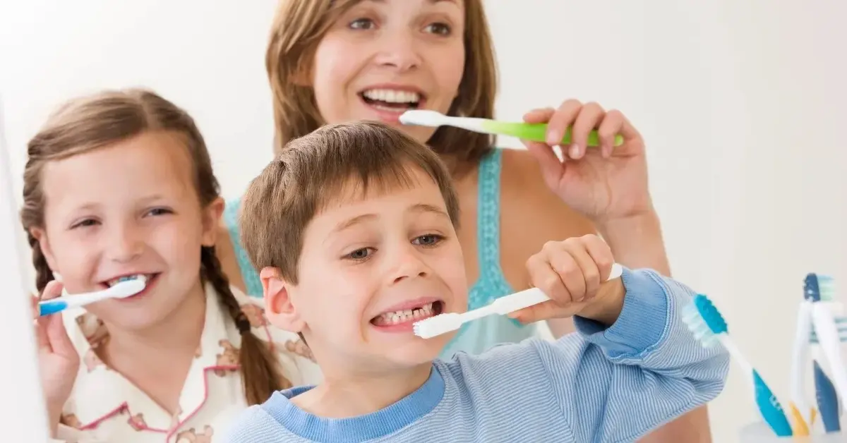Kobieta, dziewczynka i chłopiec myjący zęby 