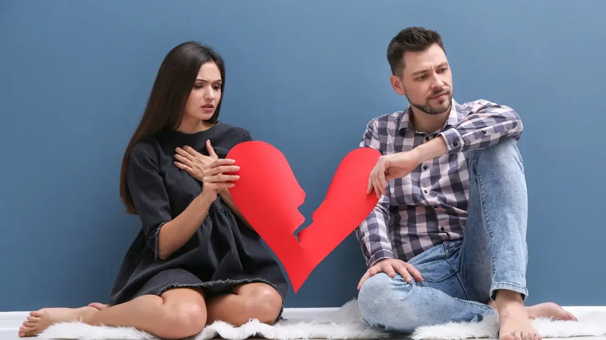 Kobieta i mężczyzna trzymający papierowe przedarte serce 