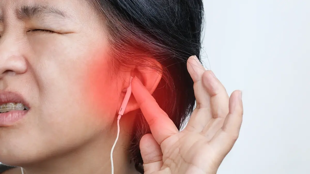 Kobieta ze słuchawka w uchu i nałożoną czerwoną grafiką sugerującą ból