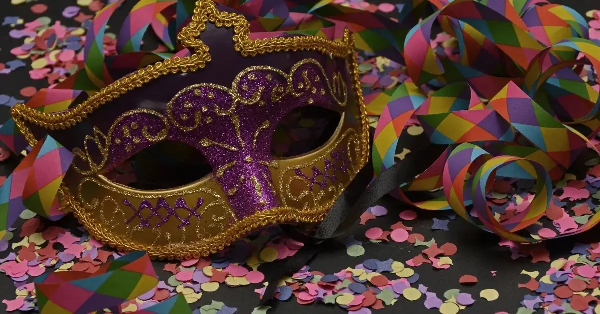 Maska karnawałowa na blacie z rozsypanym konfetti