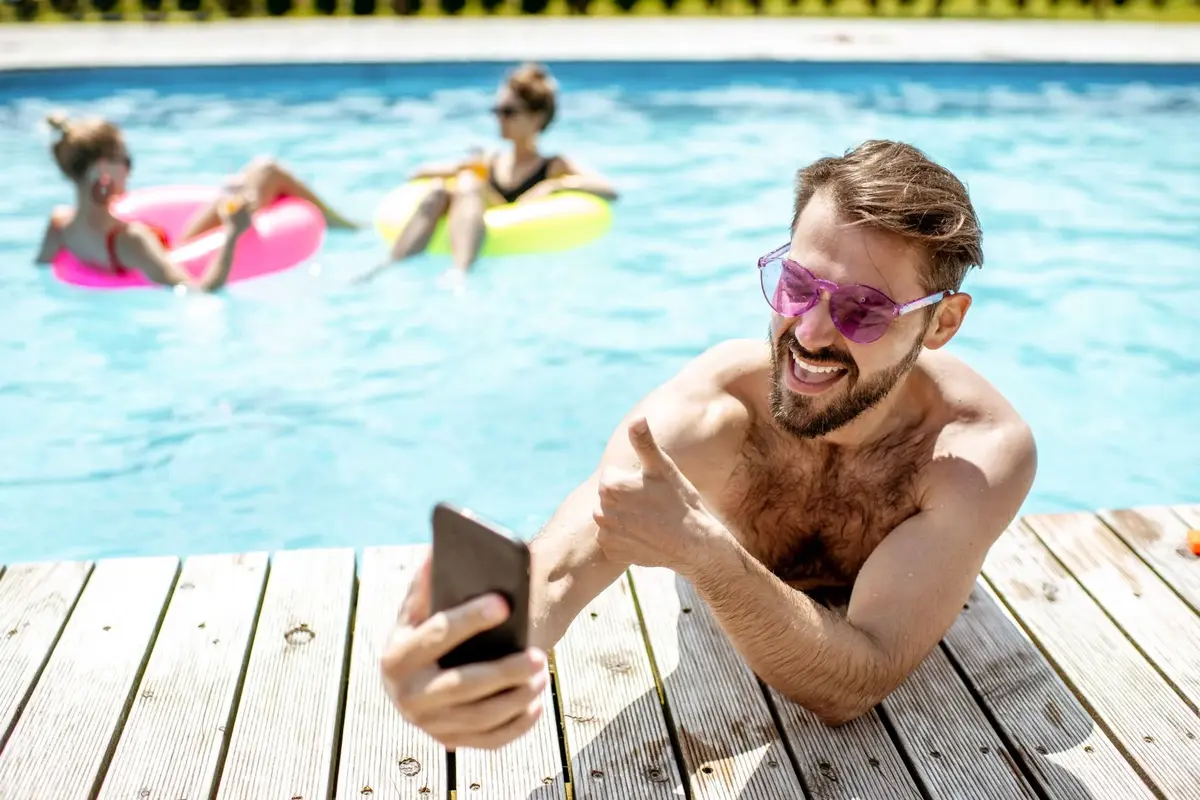 Mężczyzna na wakacjach w basenie korzysta z internetu mobilnego