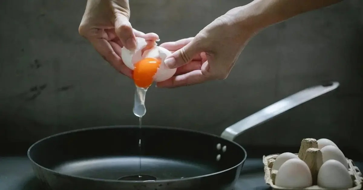 Jajka wbijane na patelnię, żeby zrobić jajecznicę.