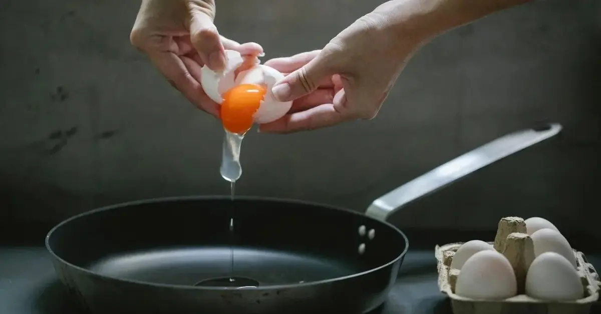 Jajka wbijane na patelnię, żeby zrobić jajecznicę.