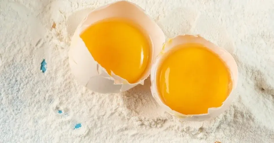 Mąka i rozbite jajka w skorupkach do naszykowania klusek leniwych.