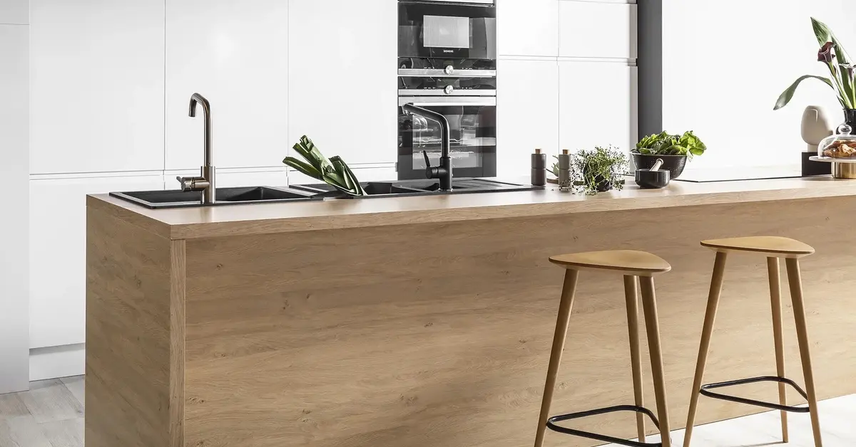 Nowoczesna kuchnia w bieli z drewnianą wyspą pośrodku ze zlewem kuchennym