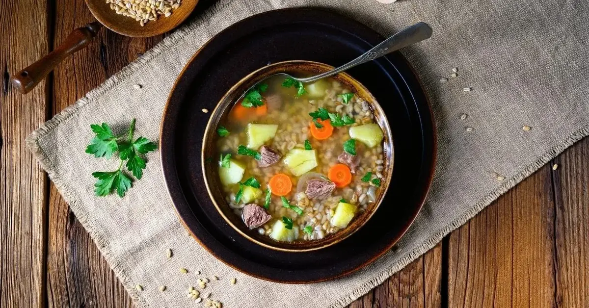 krupnik w misce stojącej na bawełnianej podkładce na drewnianym stole