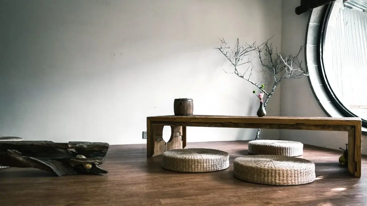 Japoński pokój w stylu wabi-sabi z drewnianym stolikiem, plecionymi poduszkami i ławą z kawałka drewna