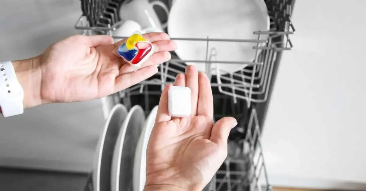 Osoba wkłąda kapsułki do zmywania do wypełnionej naczyniami zmywarki