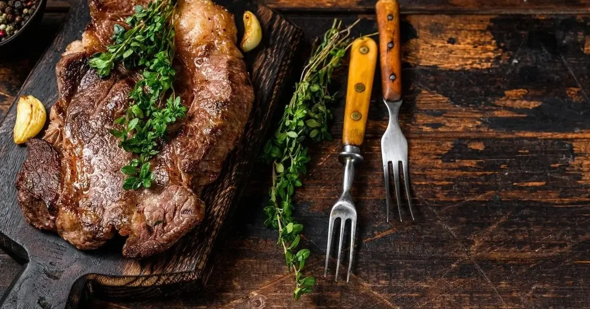 Karkówka z grilla na desce, udekorowana natką pietruszki.