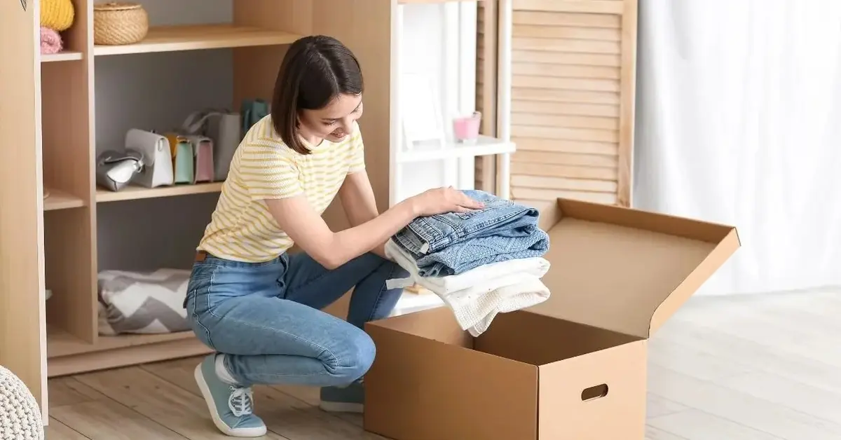 Kobieta chowa ubrania do pudełka, w celu ochrony przed molami.