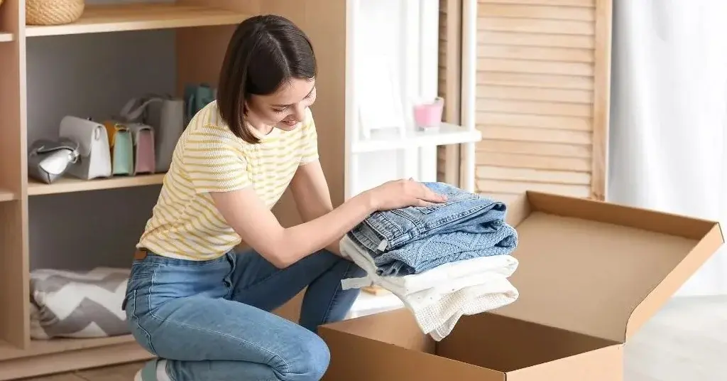 Kobieta chowa ubrania do pudełka, w celu ochrony przed molami.