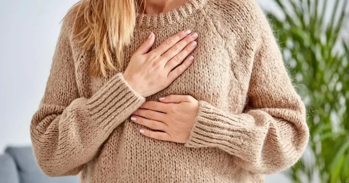Kobieta w swetrze ma arytmię serca.
