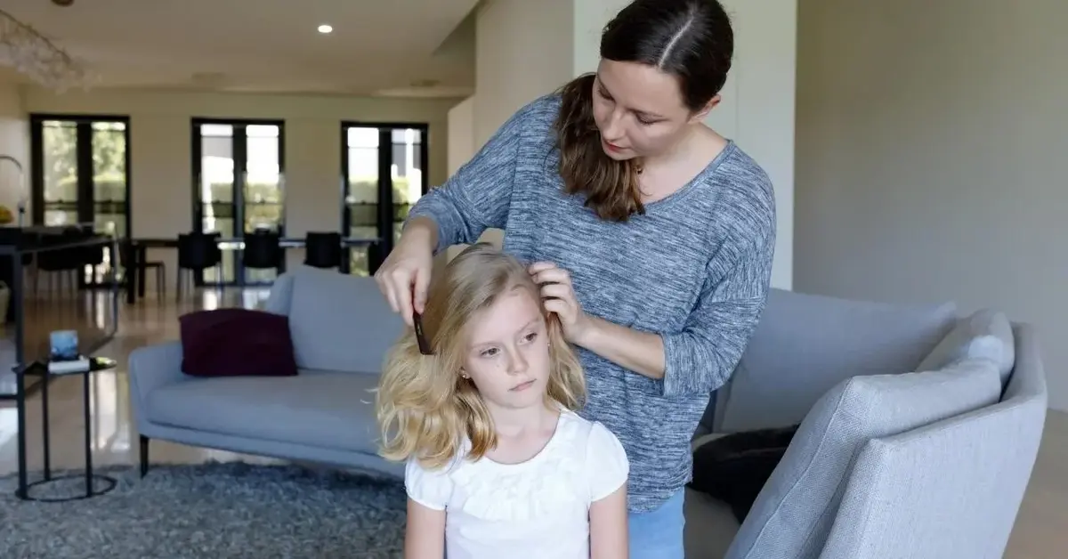 Mama wyczesuje wszy z długich włosów dziecka.