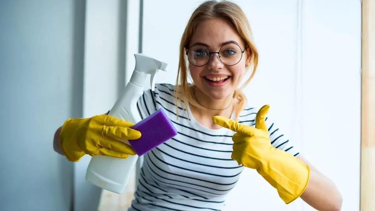 Uśmiechnięta kobieta prezentuje środki do sprzątania.