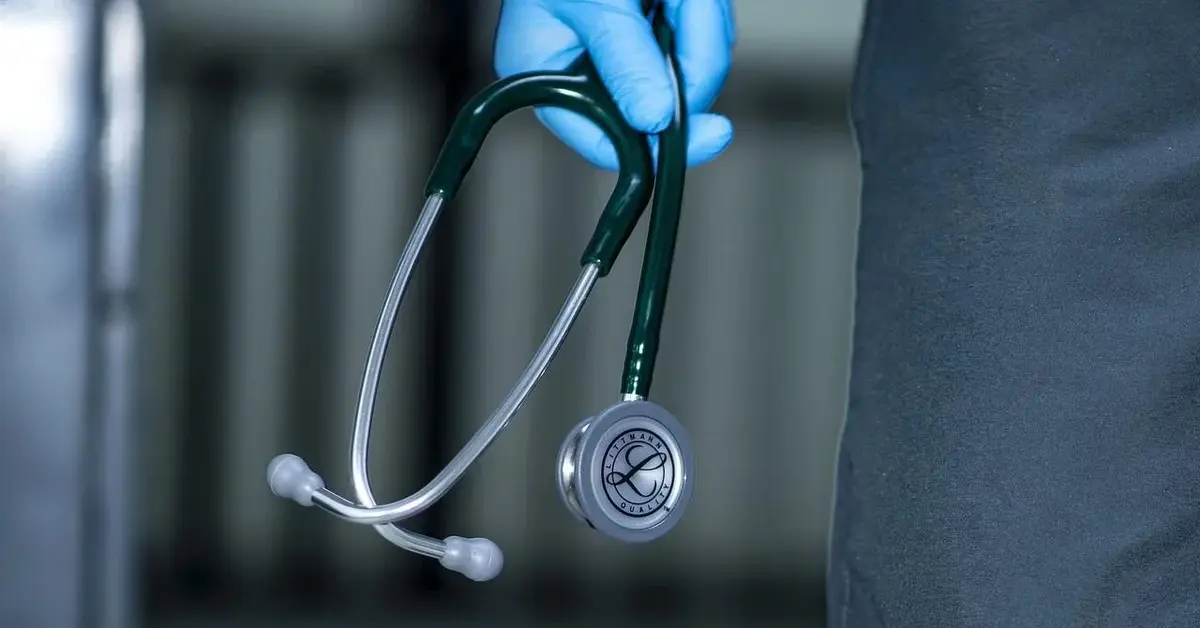 Stetoskop w dłoni lekarza ubranej w silikonową niebieską rękawiczkę medyczną