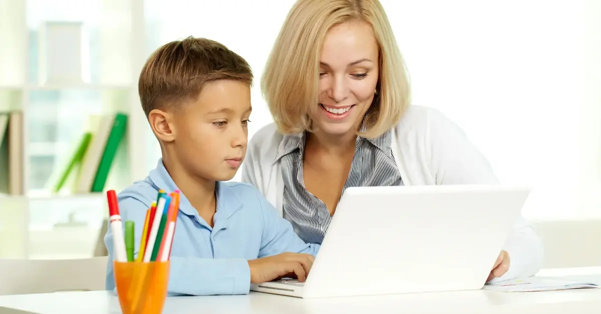 Chłopiec przy komputerze z korepetytorką w trakcie korepetycji z angielskiego