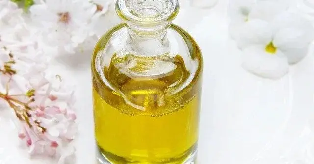 Kosmetyki naturalne - olej w szklanej butli na tle białych kwiatów