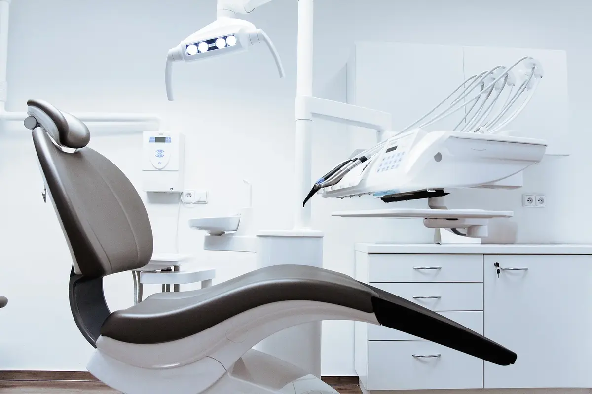 Gabinet dentystyczny ortodontyczny z fotelem na pierwszym planie utrzymane w bieli