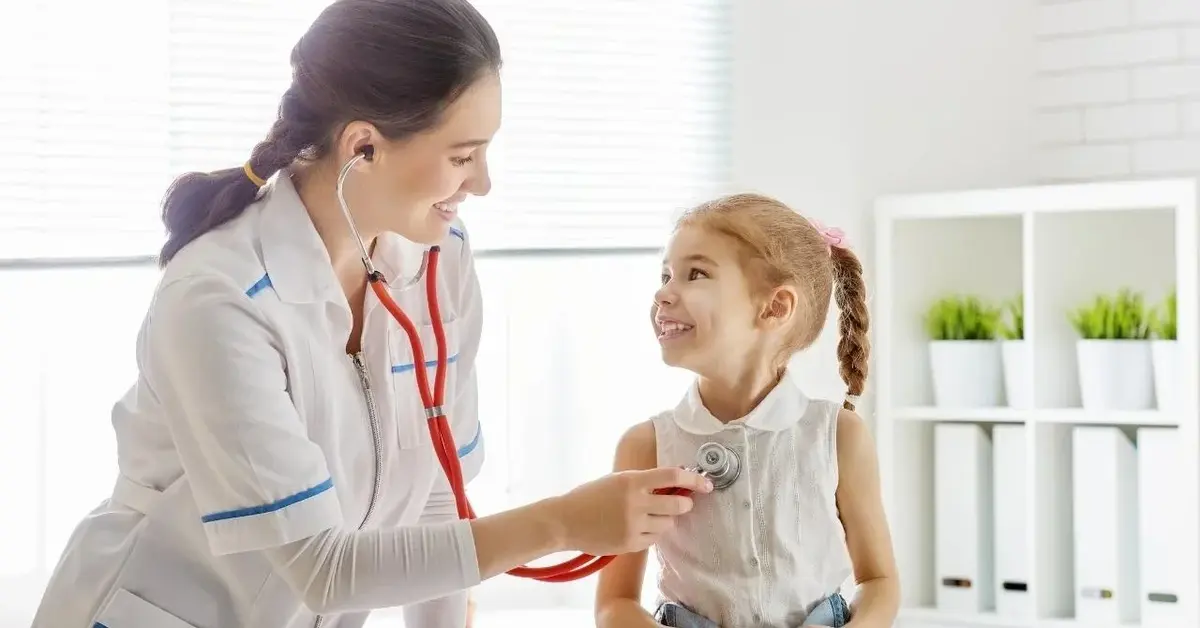 Uśmiechnięta lekarka bada uśmiechniętą dziewczynkę z bostonką.