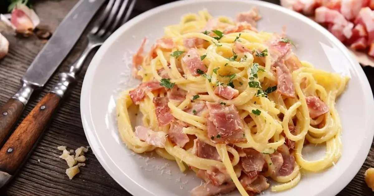 Talerz pełen makaronu z serem i jajkiem.