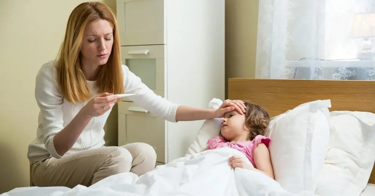 Mama sprawdza temperaturę dziecka, żeby po tym zbić gorączkę.